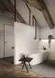 Freistehende Badewanne mit einem minimalistischen Design und einer Armatur in Silk Black von Ideal Standard. Der Boden ist mit Holz- und Steinfliesen kombiniert.
